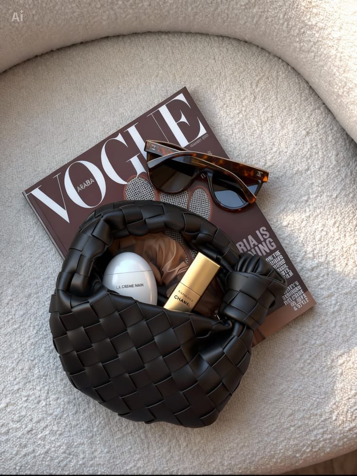 Woven black leather bag, tortoiseshell sunglasses and a Vogue magazine on a boucle chair